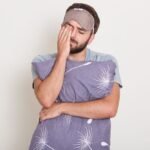 indoor shot young attractive man waking morning wants sleep handsome guy stretching yawning holding his pillos January 2026 Vadodara India
