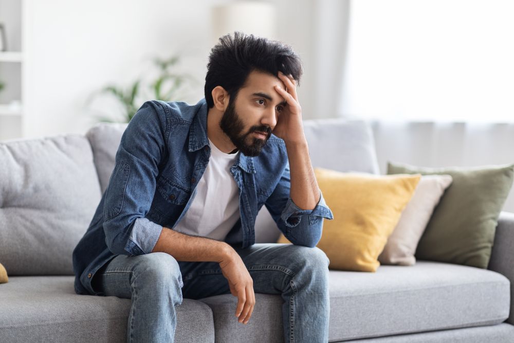From Trigger to Truth: Building a Relationship That Heals, Not Hurts 1 male depression concept upset young indian man sitting couch home October 2025 Vadodara India
